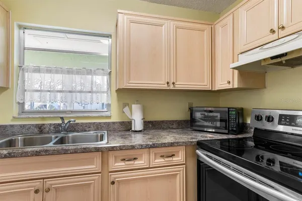 a kitchen with granite countertop a sink stainless steel appliances white cabinets and a window
