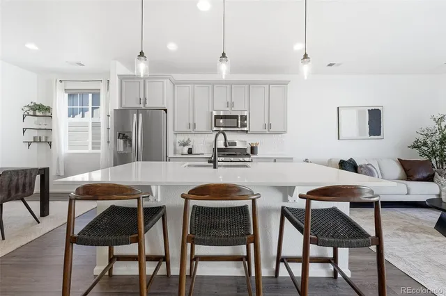 a kitchen with stainless steel appliances granite countertop a dining table chairs and white cabinets
