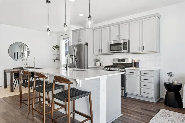 a kitchen with stainless steel appliances granite countertop a stove a sink dishwasher a refrigerator with a dining table and chairs