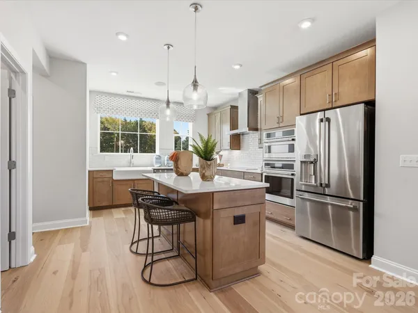 a kitchen with stainless steel appliances a dining table chairs refrigerator and microwave
