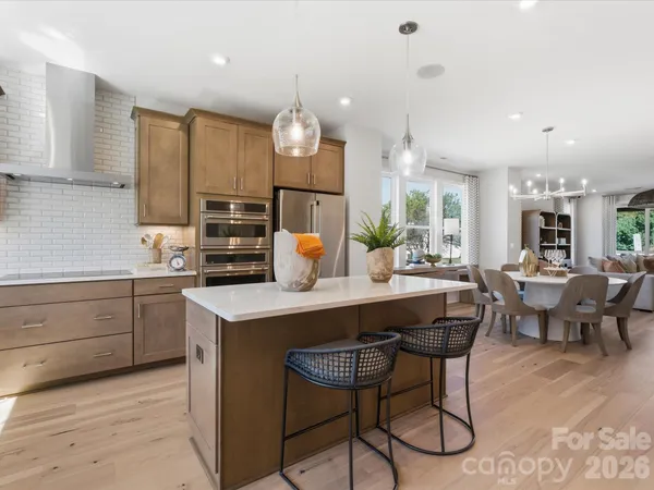a kitchen with a dining table chairs cabinets and stainless steel appliances