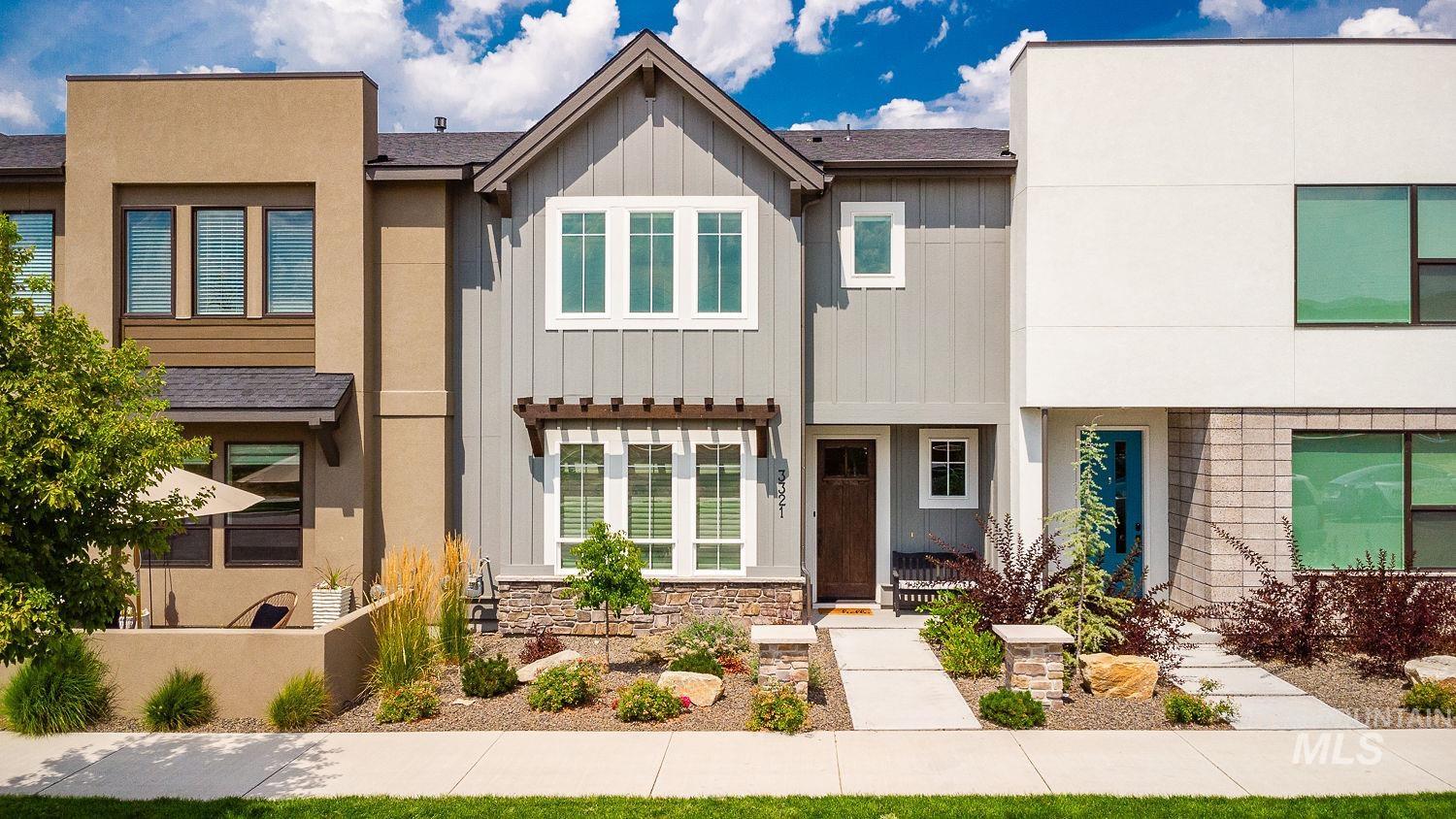 View of front of home featuring board and batten siding, stone siding, covered porch, and roof with shingles