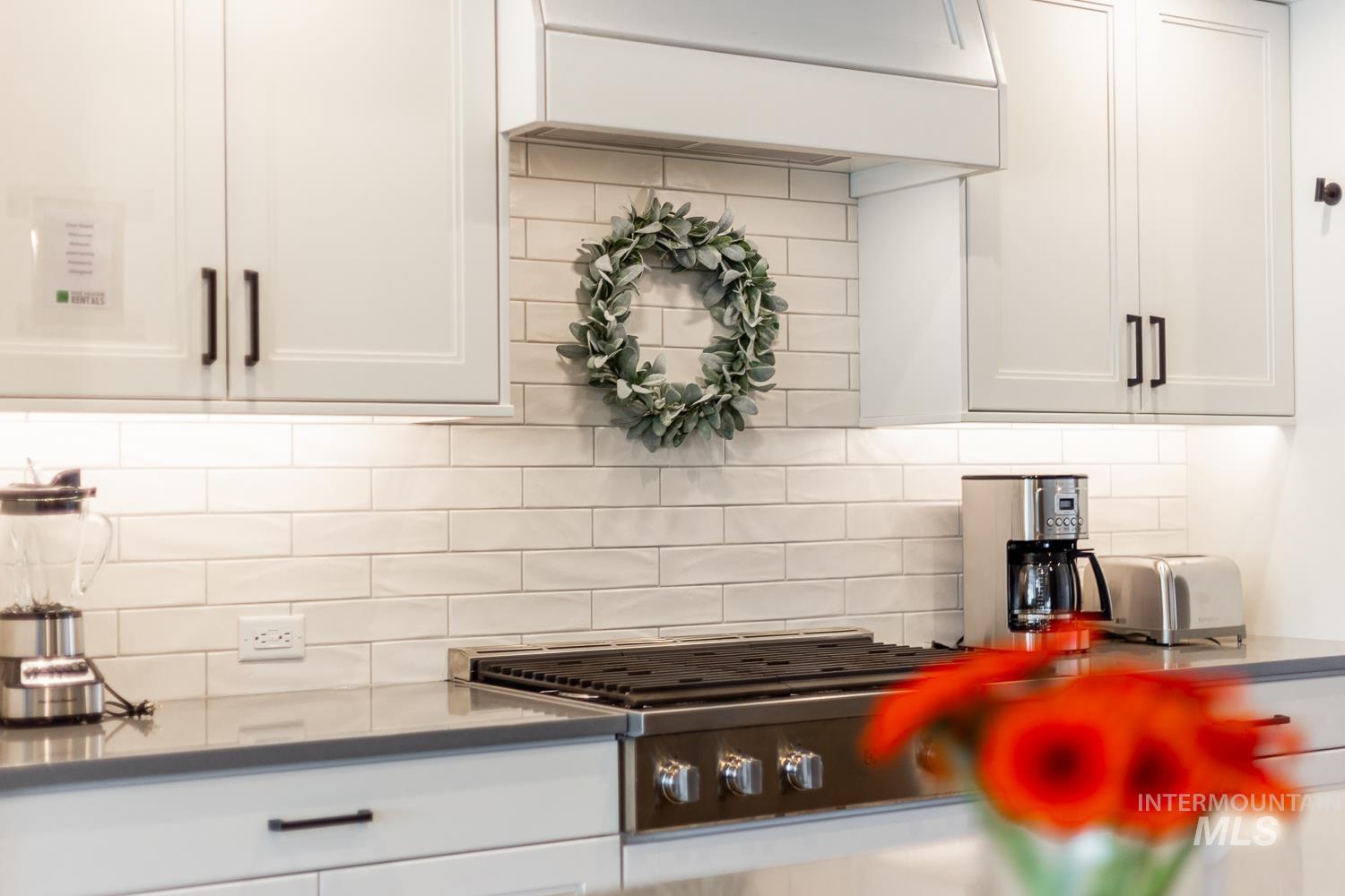 3321 South Hopes Well Way Boise, ID 83716 - Photo 20 of 40 Kitchen featuring tasteful backsplash, white cabinets, premium range hood, and stainless steel gas stovetop