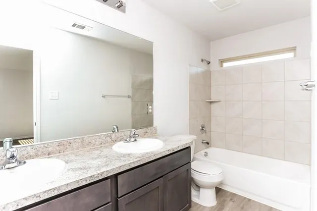 a bathroom with a granite countertop sink a toilet and bathtub