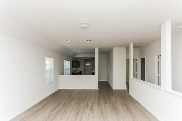 a view of a big room with wooden floor and windows