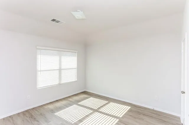 an empty room with wooden floor and windows