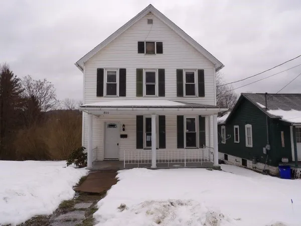a front view of a house with a yard covered in snow