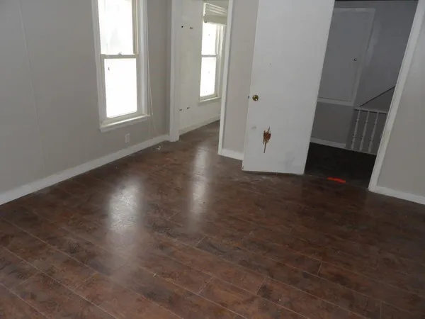 an empty room with wooden floor and windows