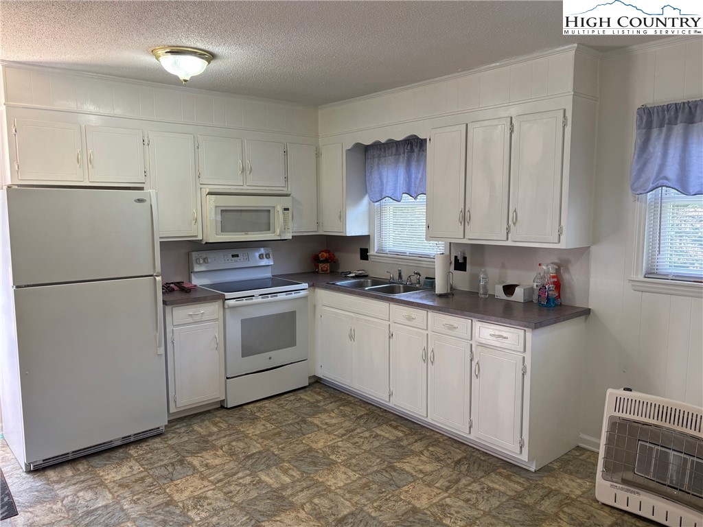 4182 Ridgeglen Road Sparta, NC 28675 - Photo 5 of 28 a kitchen with white cabinets and white appliances