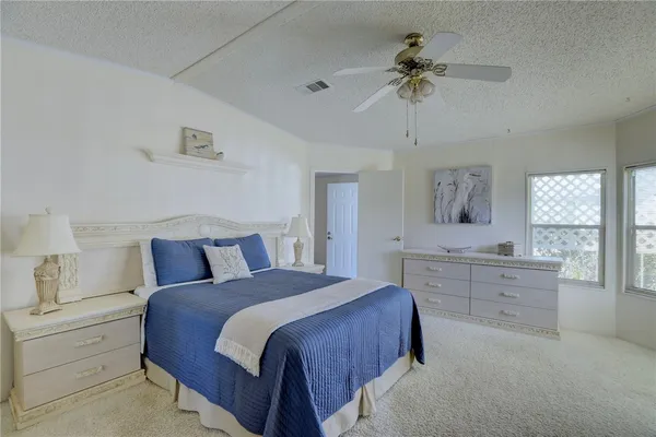 a spacious bedroom with a large bed and a chandelier fan