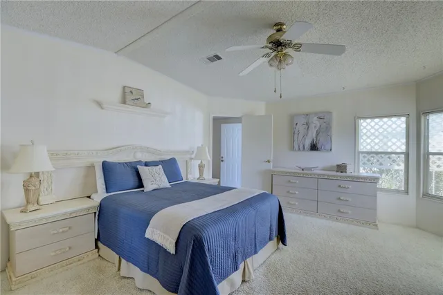 a spacious bedroom with a large bed and a chandelier fan