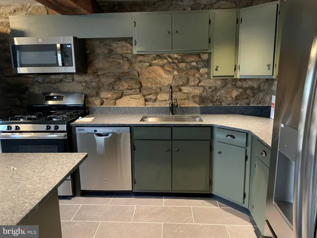 a kitchen with stainless steel appliances granite countertop a sink a stove and a microwave oven