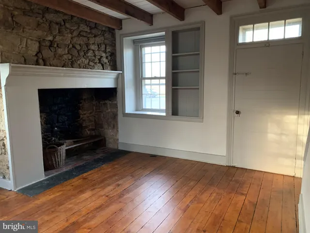 an empty room with wooden floor fireplace and windows