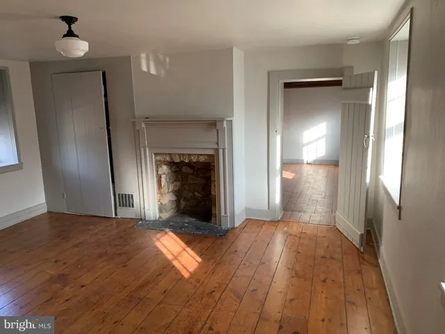 a view of empty room with wooden floor and fireplace