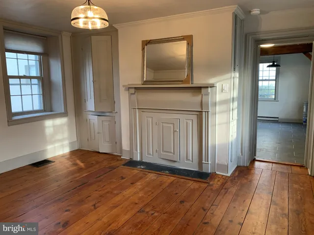 an empty room with wooden floor mirror and windows