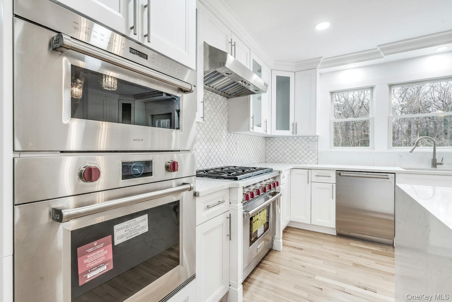 539 Split Rock Road Syosset, NY 11791 - Photo 12 of 40 Kitchen with a sink, ventilation hood, white cabinetry, and stainless steel appliances