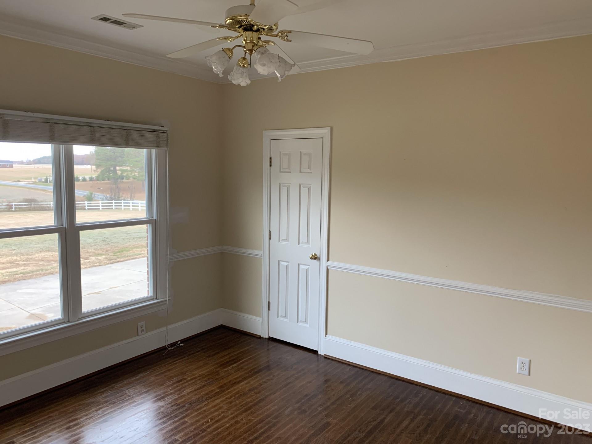 1026 Snyders Store Road Wingate, NC 28174 - Photo 30 of 34 an empty room with wooden floor chandelier fan and windows