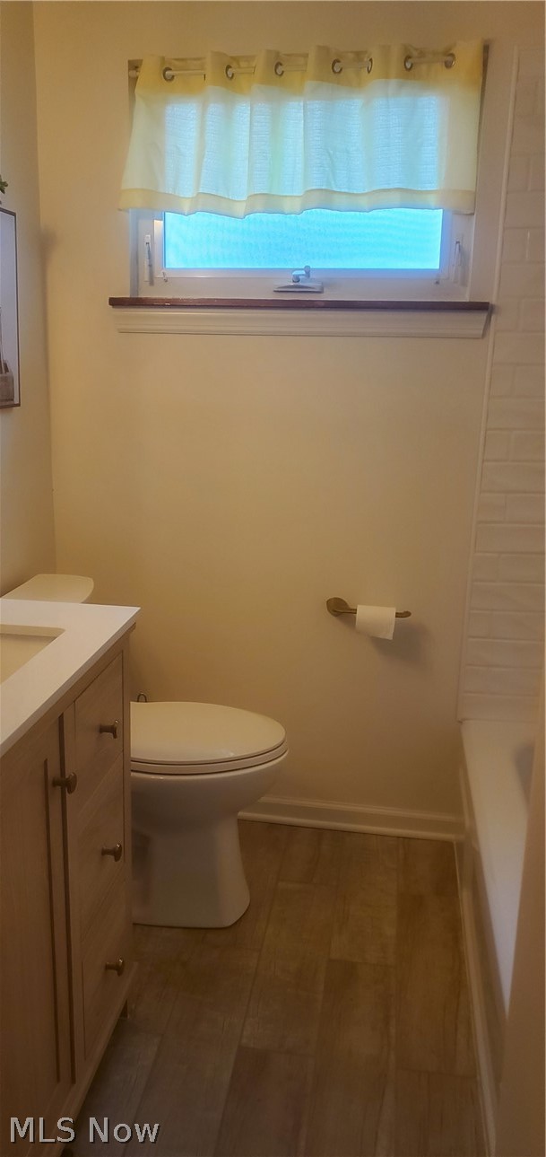 Full bathroom featuring a healthy amount of sunlight, vanity, toilet, and tile floors