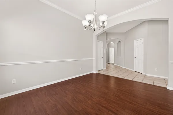 wooden floor in an empty room with a chandelier