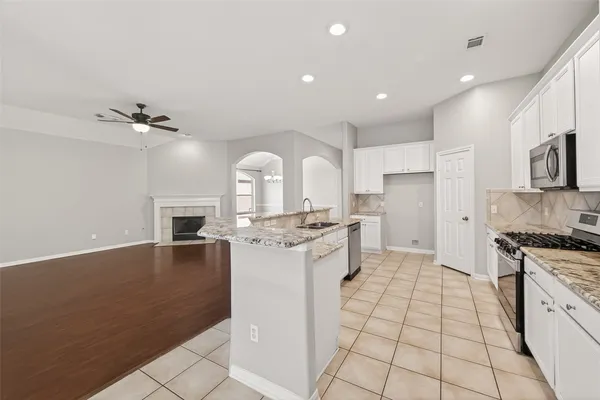 a kitchen with stainless steel appliances a sink a stove a refrigerator cabinets and living room view