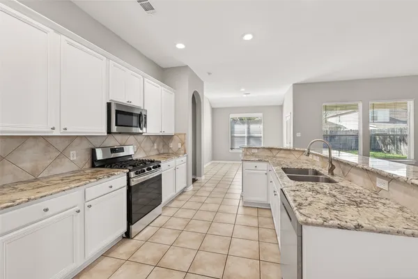 a large kitchen with a stove a sink dishwasher and a stove top oven with wooden floor