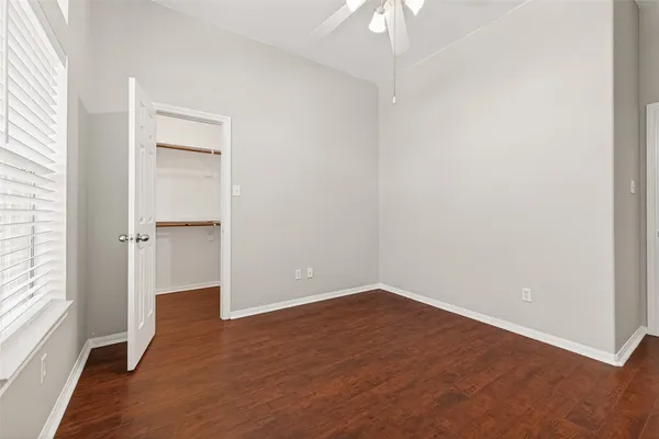 an empty room with wooden floor cabinet and windows