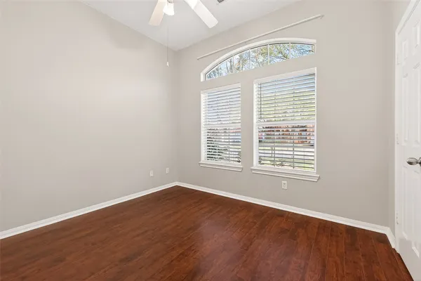 an empty room with wooden floor and windows
