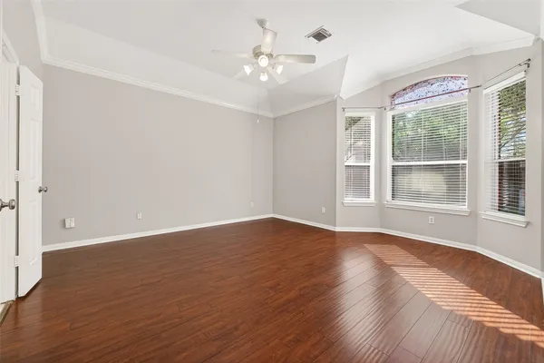a view of an empty room with wooden floor and a window