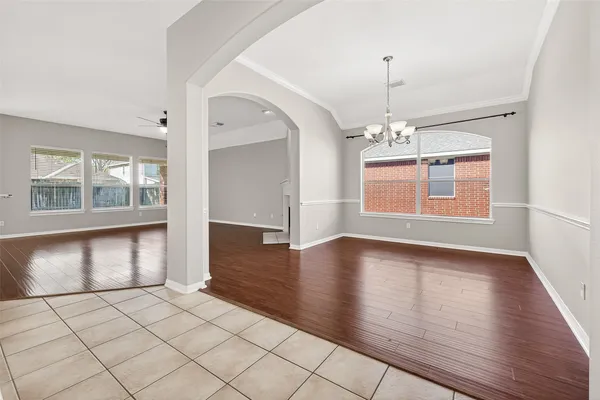 an empty room with wooden floor chandelier and windows