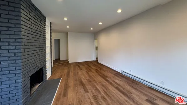 a view of wooden floor in an empty room with a fireplace