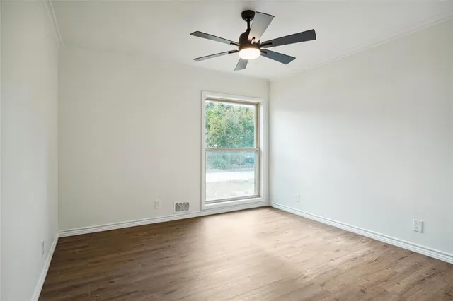 an empty room with wooden floor fan and windows