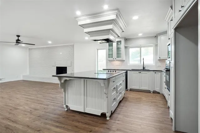 a kitchen with stainless steel appliances granite countertop a sink a stove a refrigerator and island with wooden floor