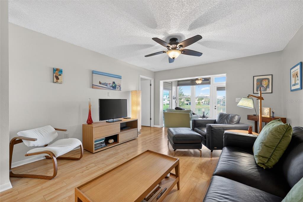 1438 Millstream Lane, Unit 105 Dunedin, FL 34698 - Photo 12 of 34 a living room with furniture a large window and a flat screen tv