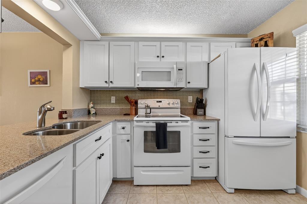 1438 Millstream Lane, Unit 105 Dunedin, FL 34698 - Photo 5 of 34 a kitchen with white cabinets and white appliances