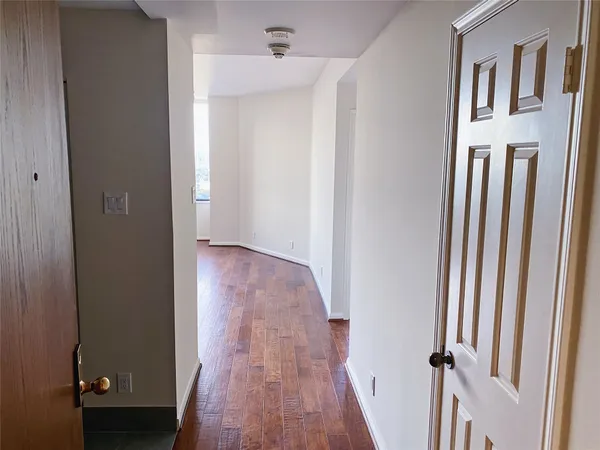a view of a hallway with wooden floor and a bathroom
