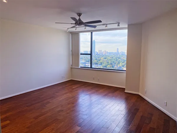 a view of an empty room with wooden floor and a window