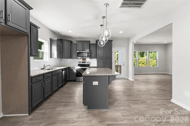 a large kitchen with granite countertop a large counter top space a sink stainless steel appliances and cabinets