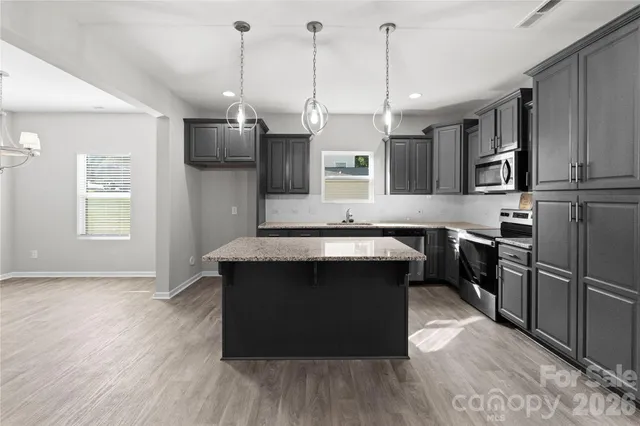 a kitchen with kitchen island a counter top space a sink appliances and cabinets