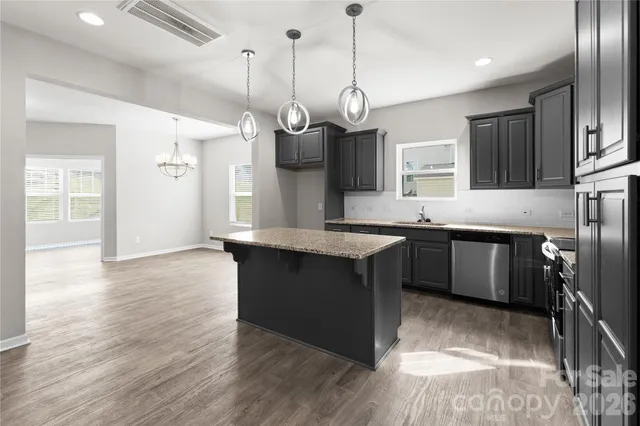 a kitchen with stainless steel appliances granite countertop a sink a stove and a wooden floor