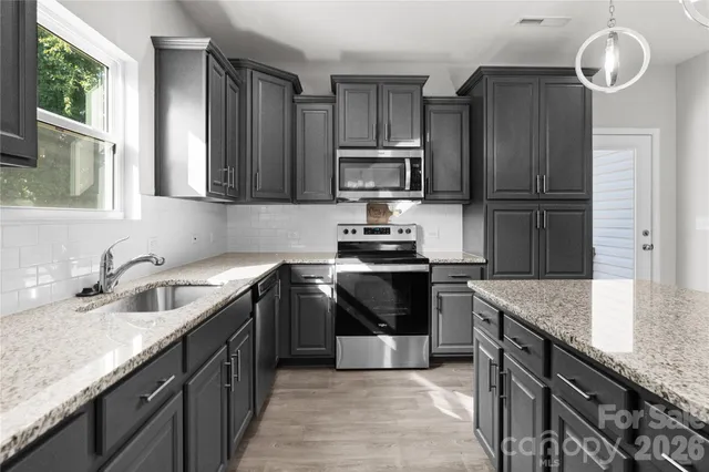 a kitchen with kitchen island granite countertop stainless steel appliances a sink stove and refrigerator