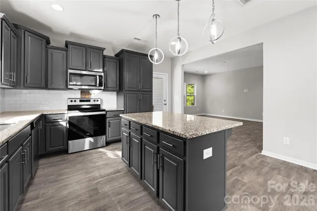 a kitchen with stainless steel appliances granite countertop a stove top oven a refrigerator and a sink