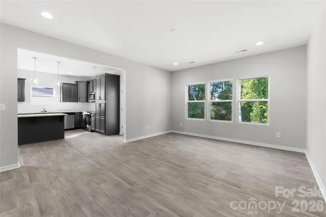 an empty room with windows and kitchen view