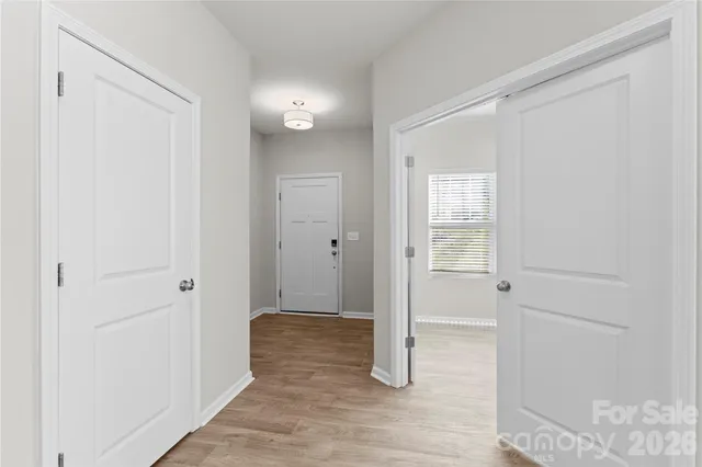 a view of a hallway with wooden floor and a bathroom
