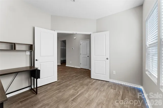 an empty room with wooden floor and windows