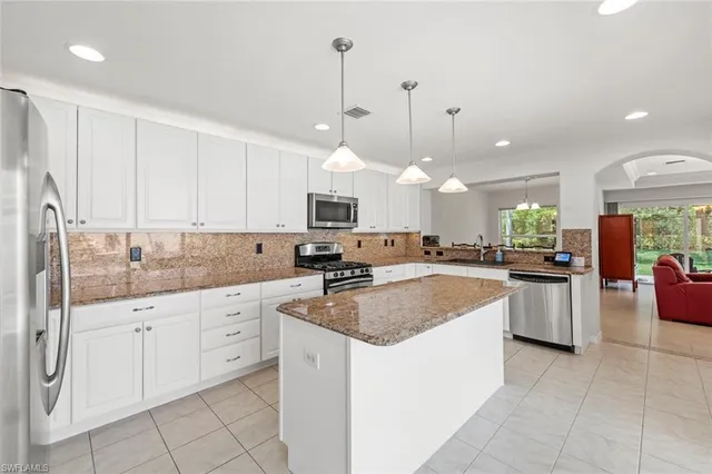 a large kitchen with stainless steel appliances granite countertop a sink a stove a refrigerator and a cabinets