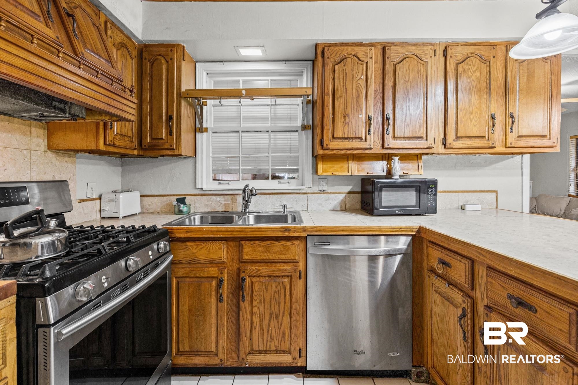5510 Richmond Road Mobile, AL 36608 - Photo 4 of 21 Kitchen featuring wood cabinetry, stainless steel gas range, stainless steel dishwasher, double basin stainless steel sink, and light-toned countertops