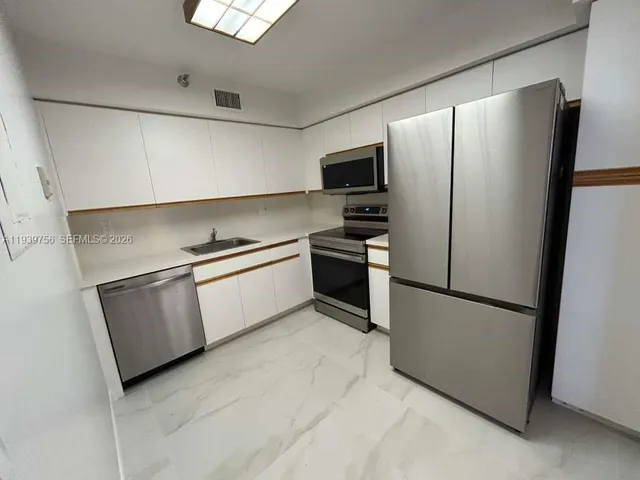 a kitchen with stainless steel appliances a refrigerator a stove a sink a microwave and cabinets