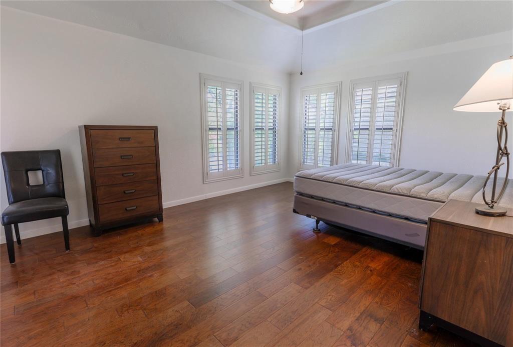 224 Sovereign Court Rockwall, TX 75032 - Photo 11 of 16 a bedroom with a bed and wooden floor