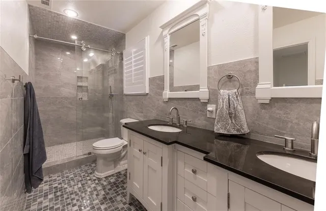 a bathroom with a granite countertop sink a toilet a mirror and shower