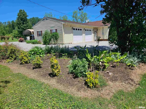 a front view of a house with a yard and garden